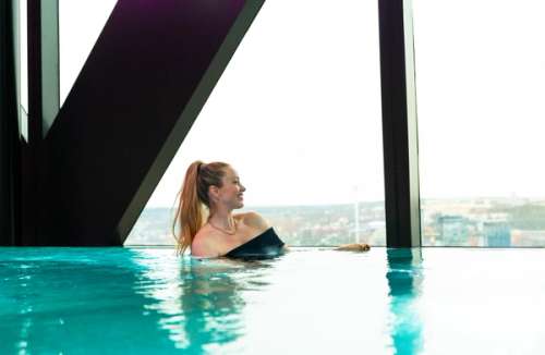 Woman in a pool looks out the window at the view.