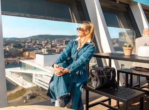 Kvinne nyter utsikten fra takterrasse.