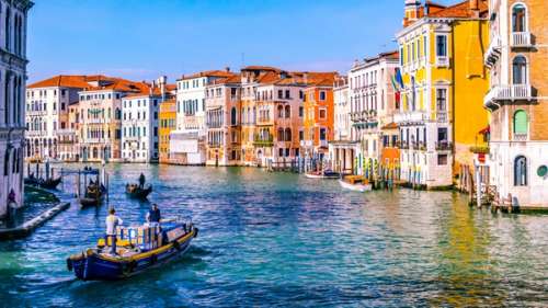 En kanal i Venezia med fargerike bygninger og båter.