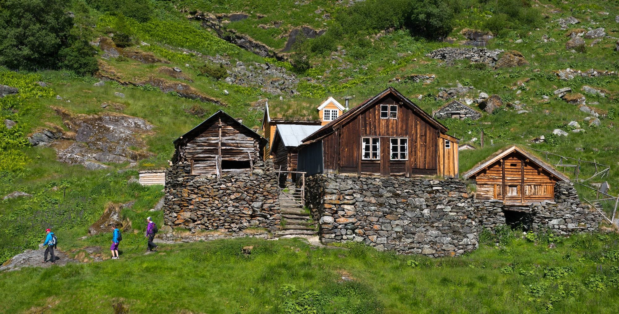 Tre personer går tur forbi en gammel hytte.