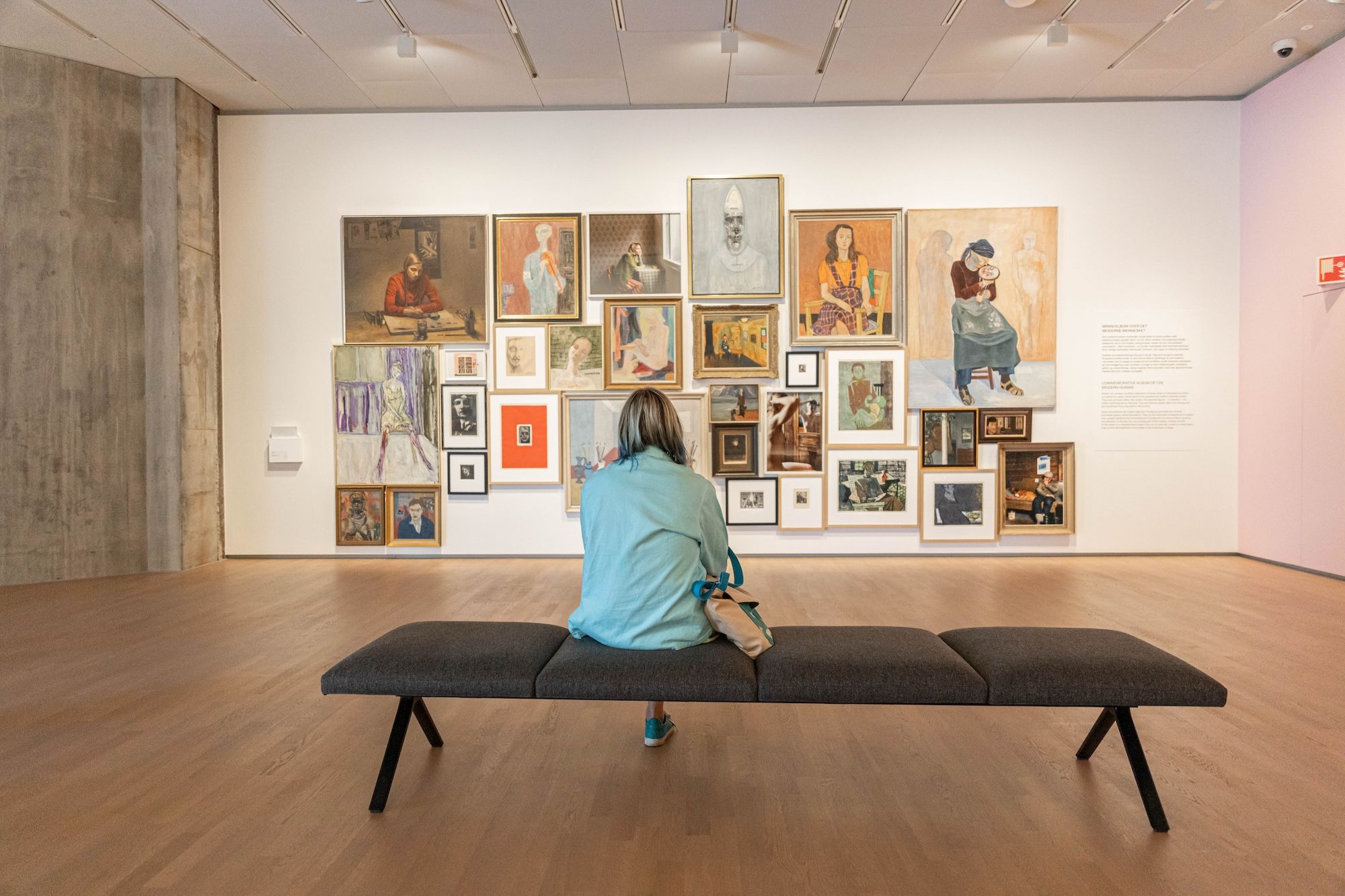A woman sits with her back to the camera, looking at a wall of images.