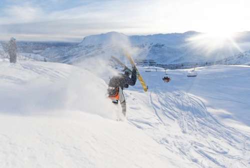 Person tricks with a front flip on skis down the ski resort.