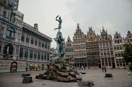 Gamle bygninger som omringer en statue med fontene.