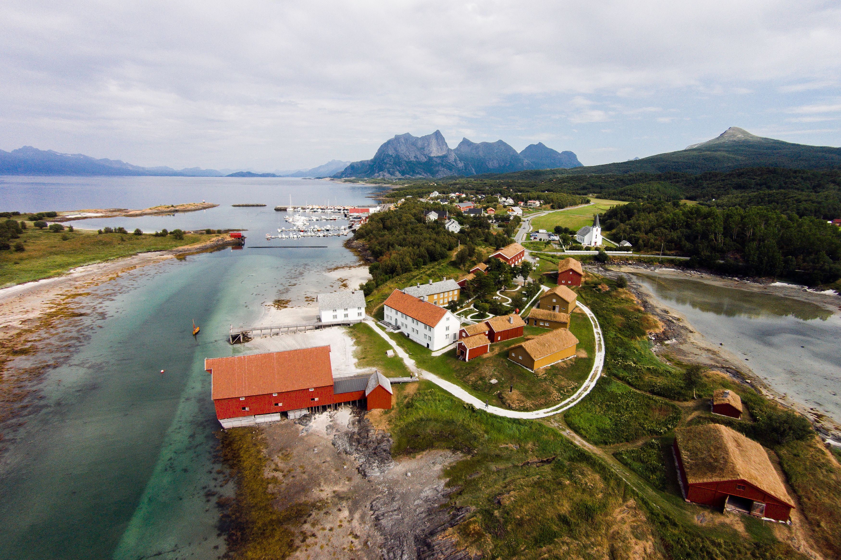 Kjerringøy, historisk kommersielt sentrum, bygninger foran med marina lengre bak. fjelli bakgrunnen