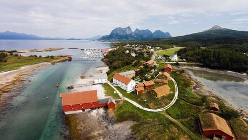 Kjerringøy, historisk kommersielt sentrum, bygninger foran med marina lengre bak. fjelli bakgrunnen