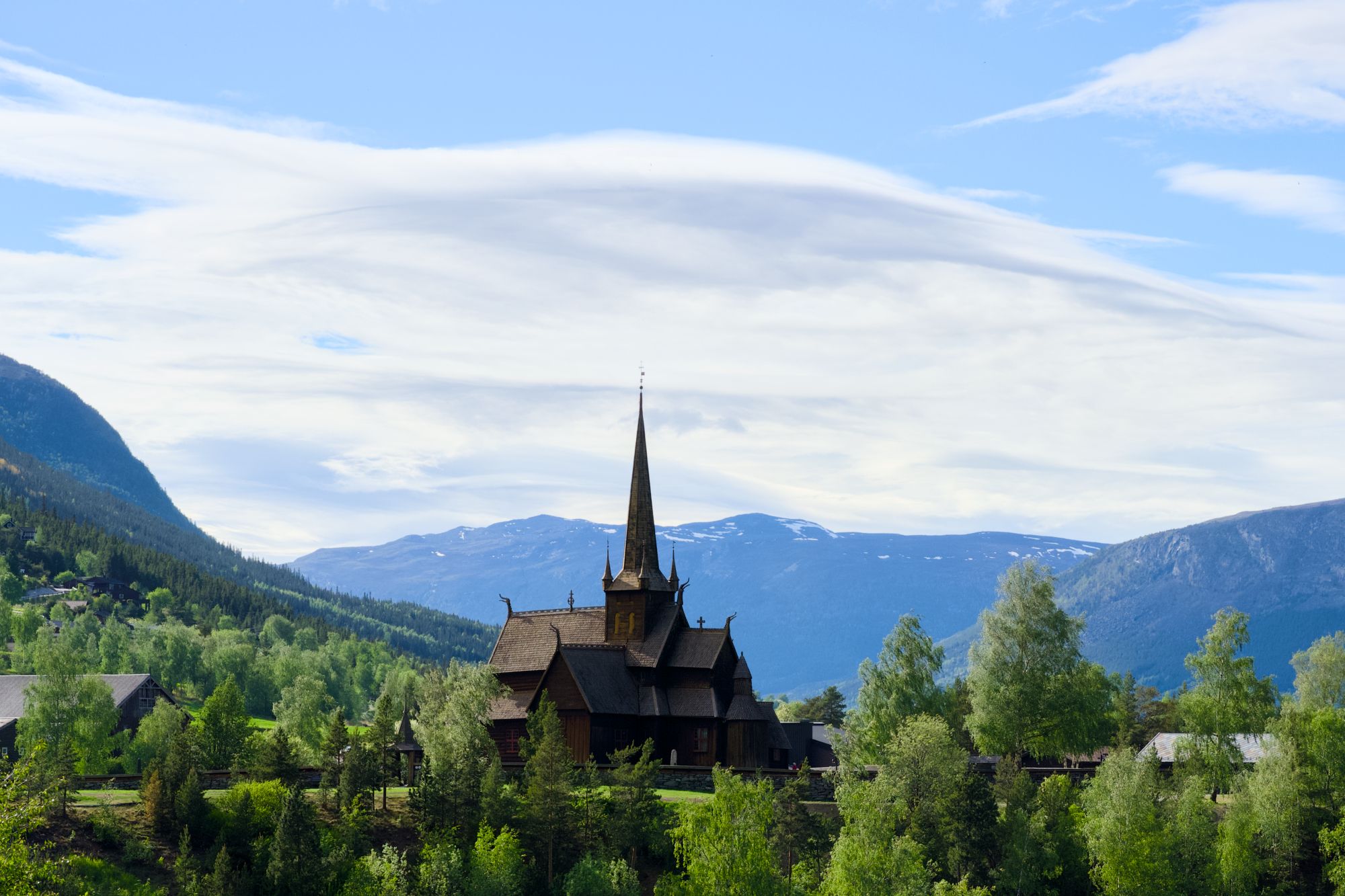 Lom Stavkirke omringet av grønn skog.