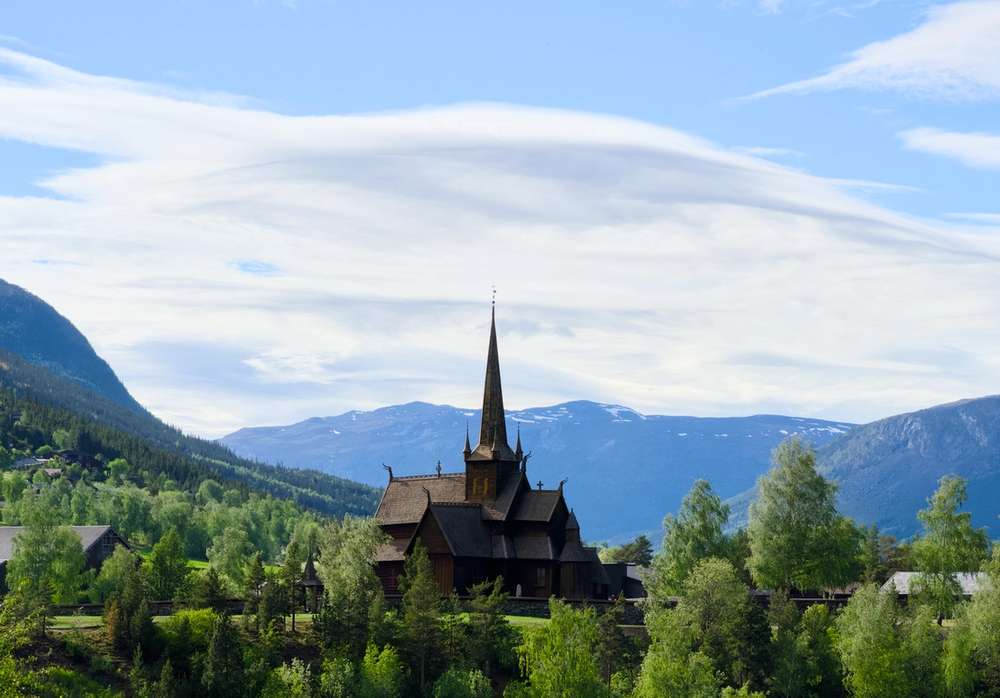 Lom Stavkirke omringet av grønn skog.