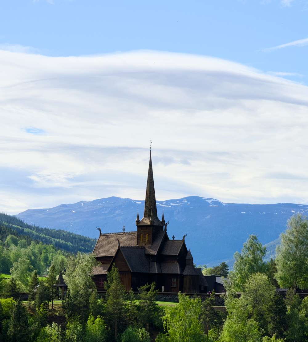 Lom Stavkirke omringet av grønn skog.