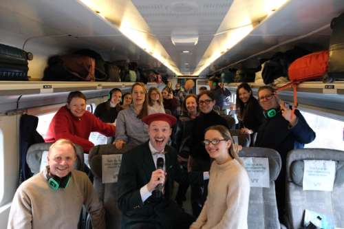 Group of people standing together on the train looking into the camera and smiling.