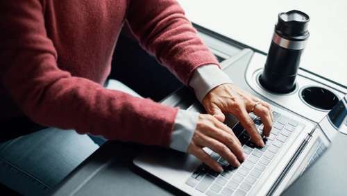 En person sitter å taster på pc som står på bordet