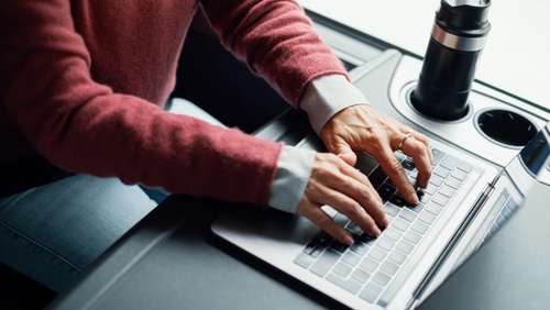 One person is typing on a PC on the table