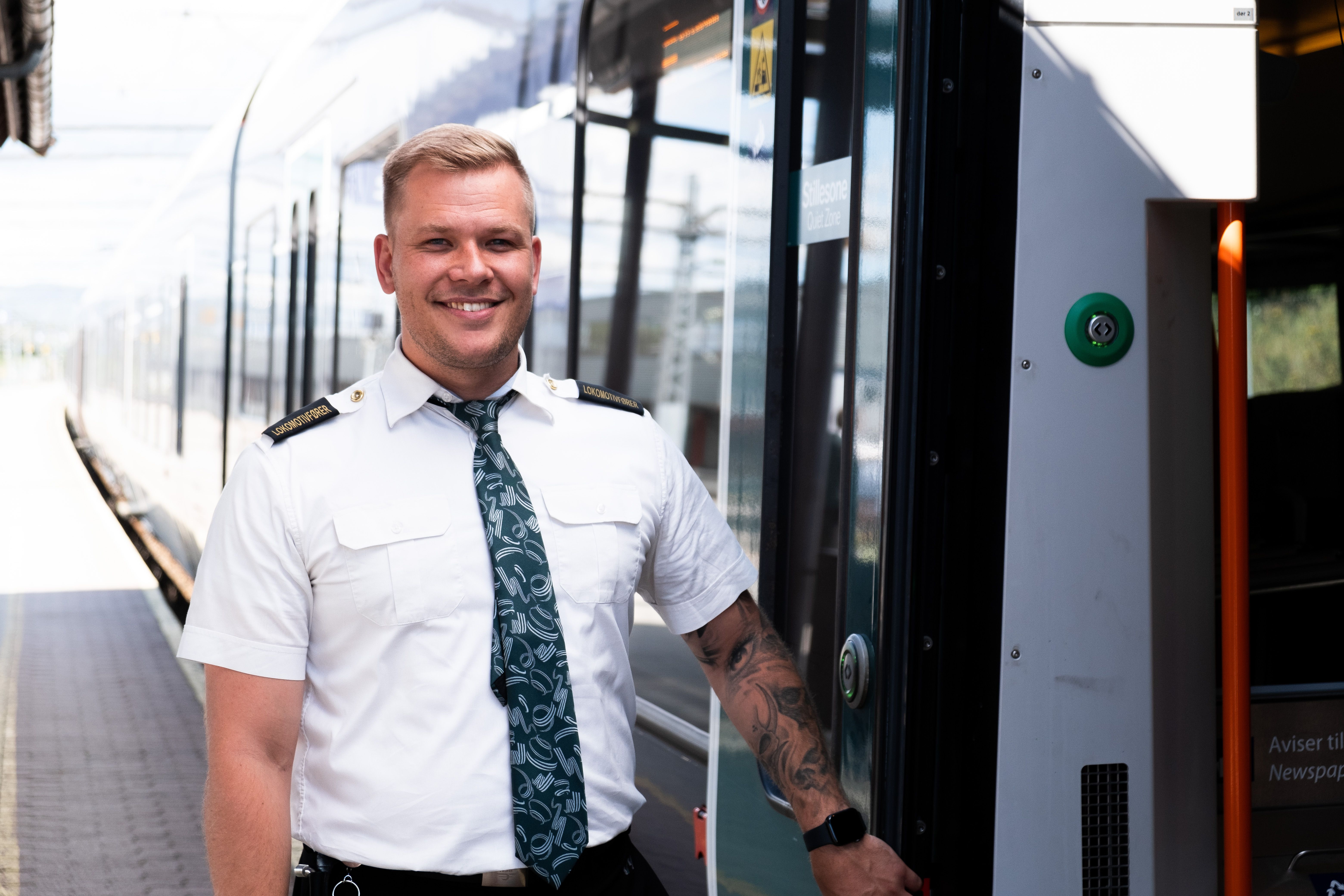 Train driver Kenneth stands outside a train and smiles