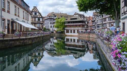 Gamle bygninger og fargerike blomster langs en kanal.