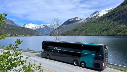 Vy dobbeldekker i en busslomme ved en fjord med fjell i bakgrunnen