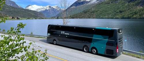 En dobbeldekker som står parkert langs fjord og fjell.