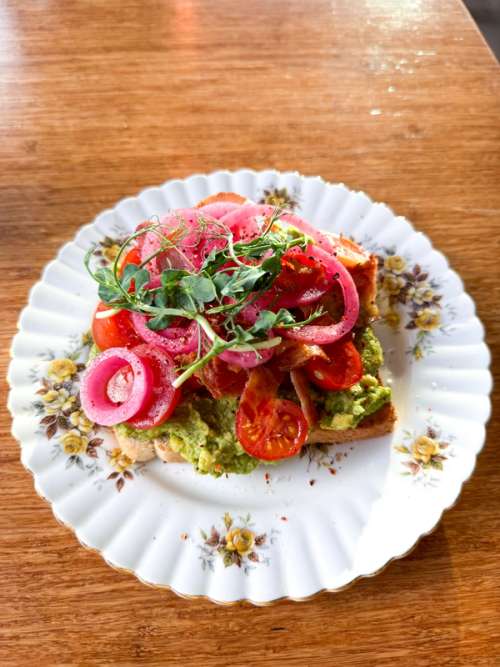 Avokadotoast servert med sylta raudlauk og cherrytomatar.