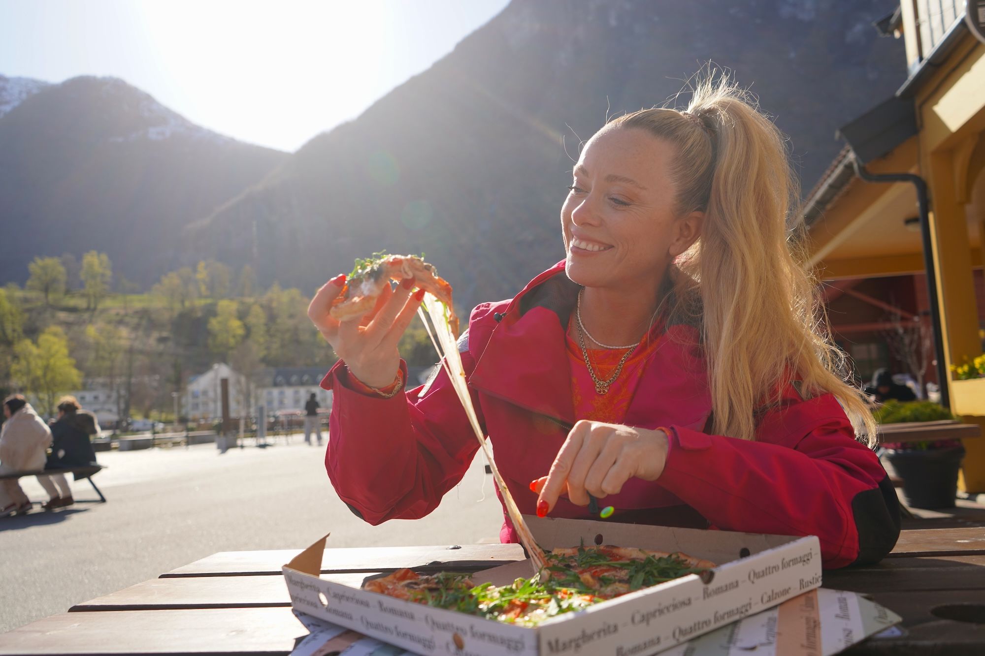 Smiling woman holding a slice of pizza.