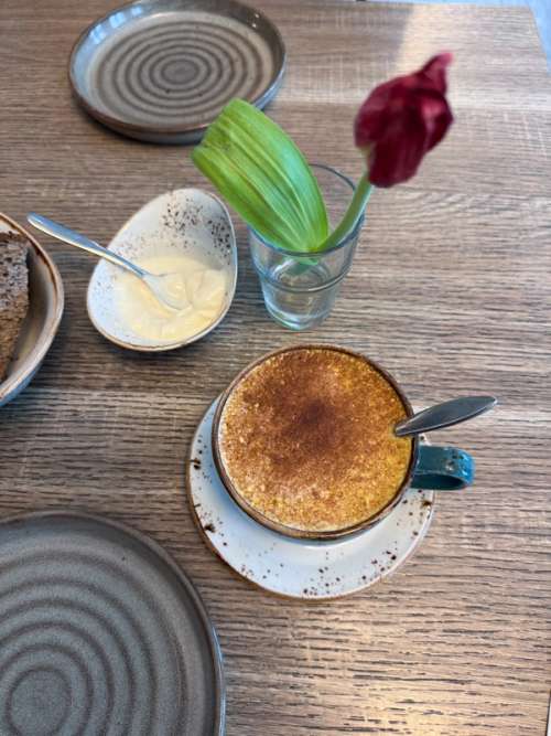 Table covered with a plate, Golden milk and a vase with a red tulip.