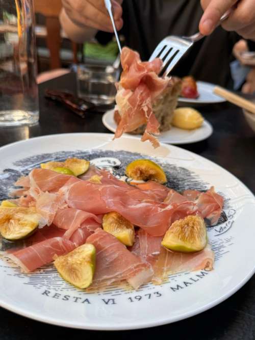 Plate filled with Serrano ham, with cutlery lifting a portion.