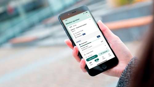 En hånd som holder en mobil hvor skjermen viser Smartpris i Vy-appen