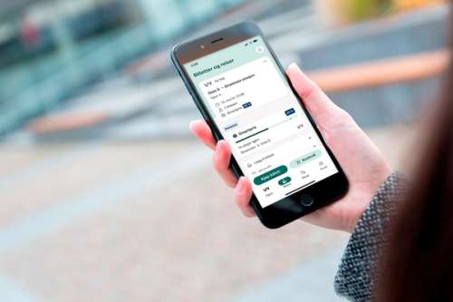 En hånd som holder en mobil hvor skjermen viser Smartpris i Vy-appen