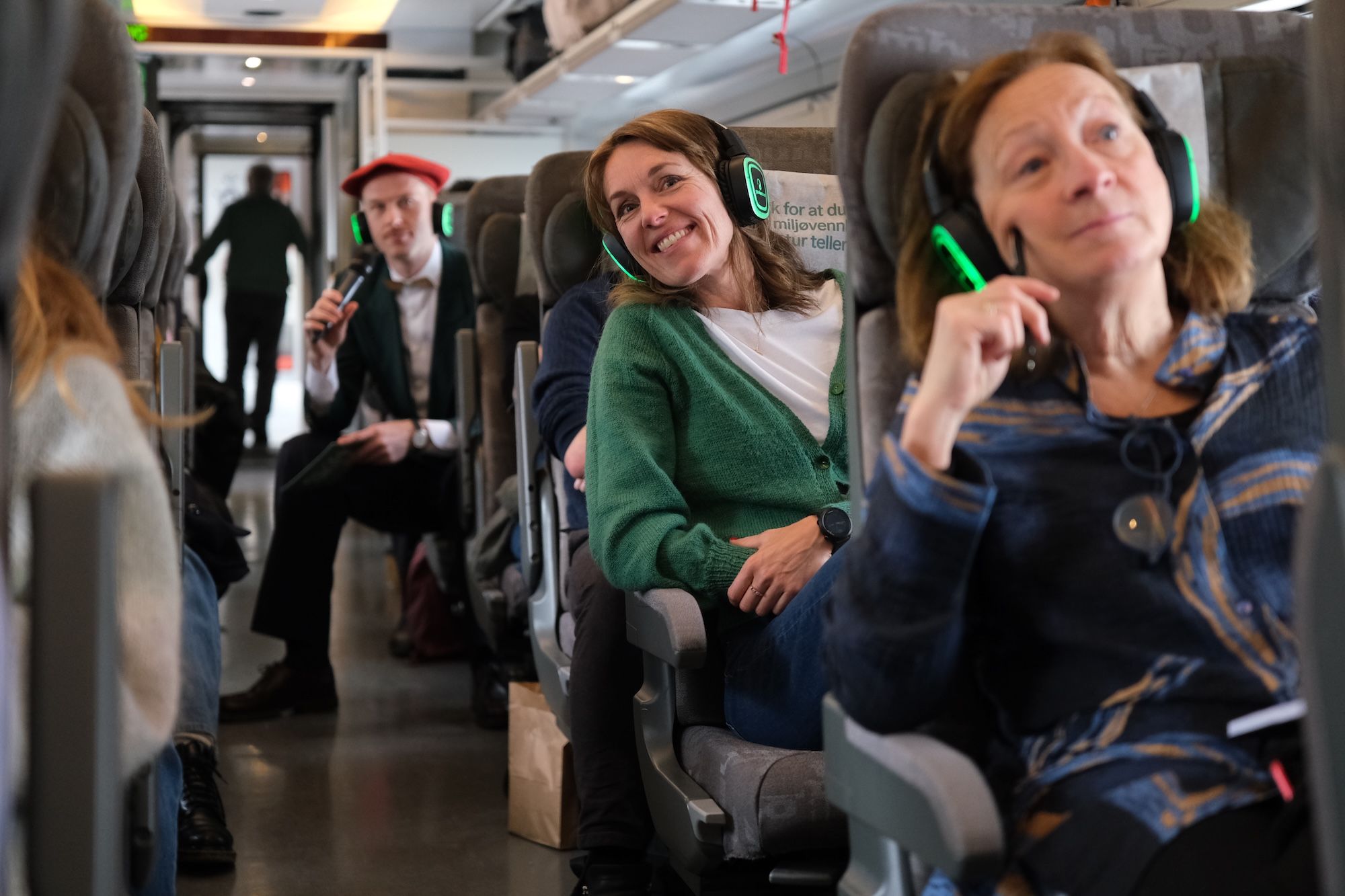 People sitting on the train with headphones on, listening to an audio guide.