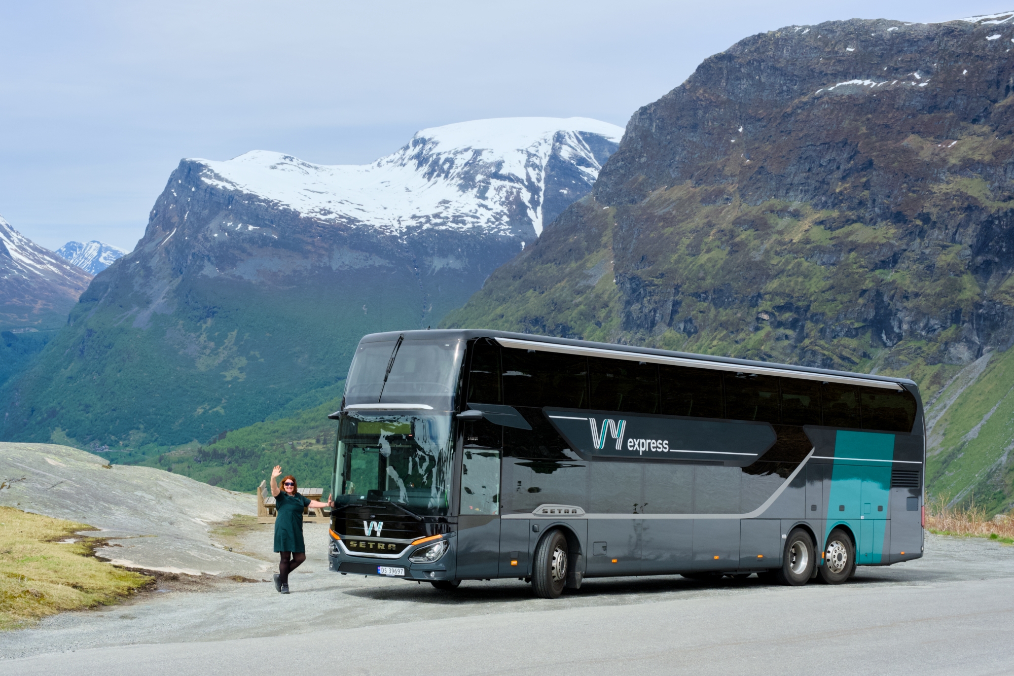 En Vy-buss som står parkert med fjell i bakgrunnen
