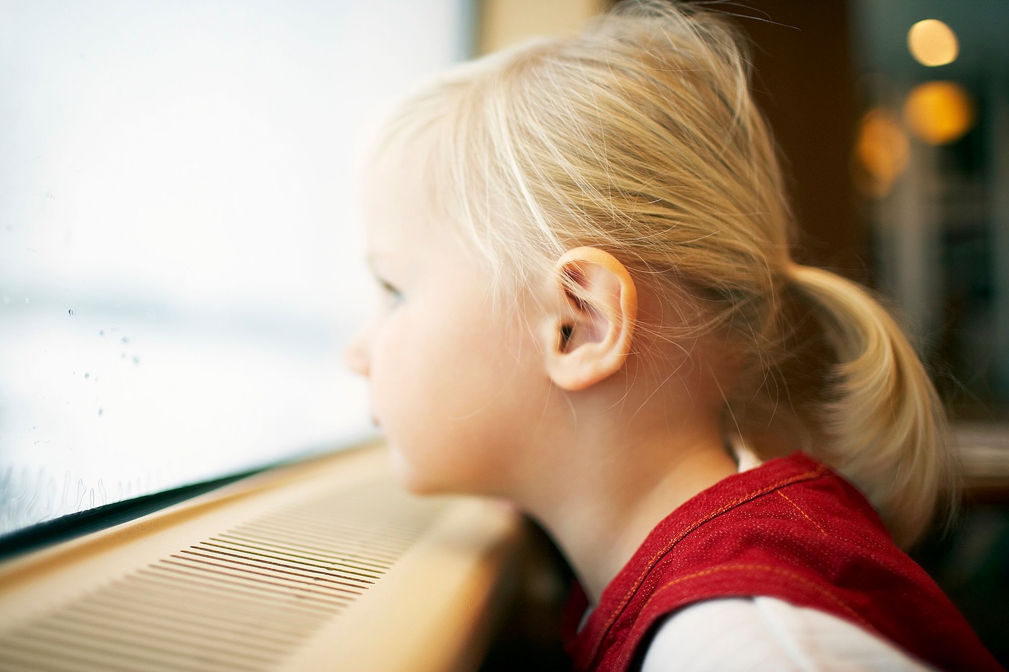 En liten jente på toget som ved vinduskarmen, og ser ut av togvinduet
