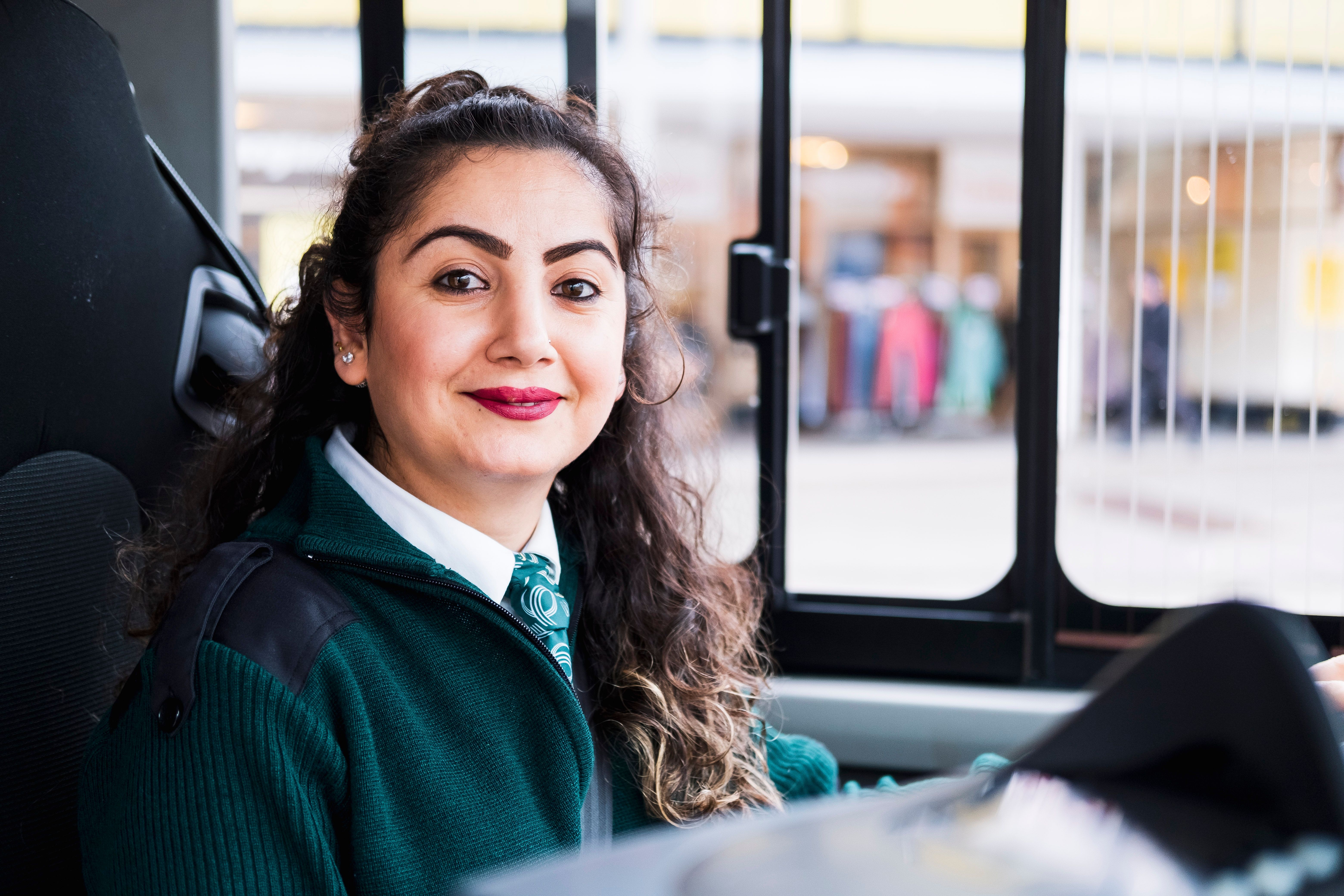 Kvinnelig bussjåfør med uniform i førersetet