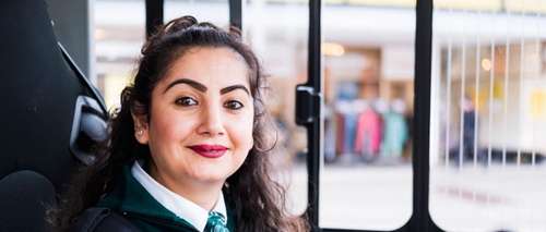 Kvinnelig bussjåfør med uniform i førersetet