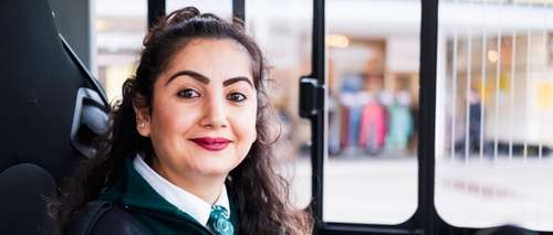 Kvinnelig bussjåfør med uniform i førersetet