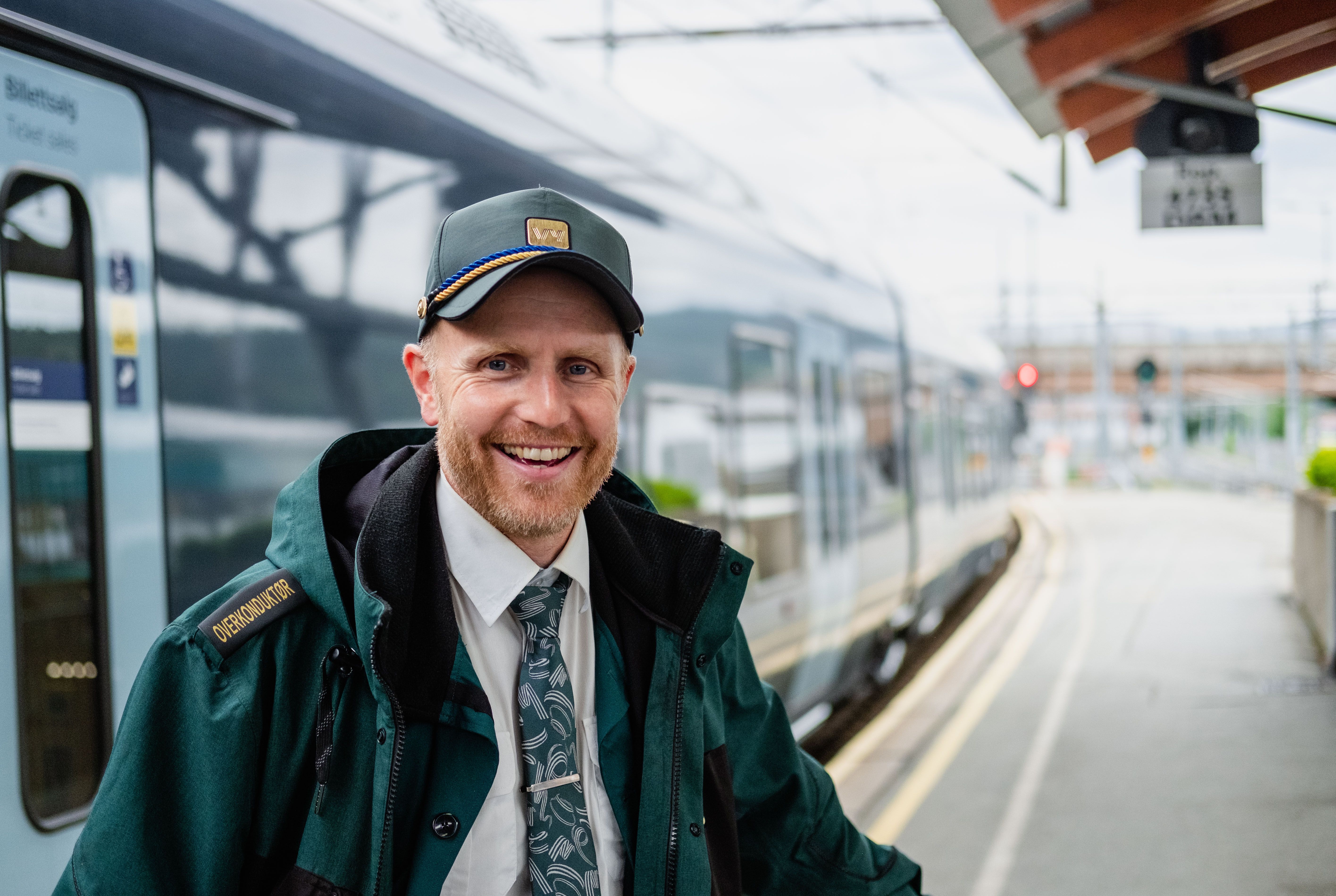 Conductor Sveinung stands outside a train and smiles