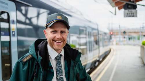 Conductor Sveinung stands outside a train and smiles