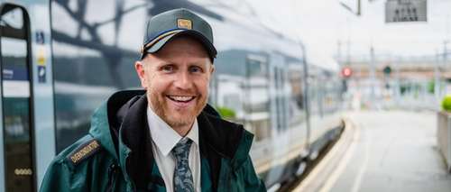 Conductor Sveinung stands outside a train and smiles
