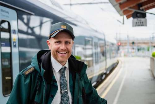 Konduktør Sveinung står utenfor et tog og smiler