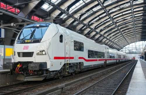 Hvitt tog på en platform i en togstasjon.