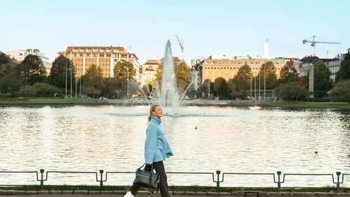 A woman with a blue sweater walking along a pond in Bergen.