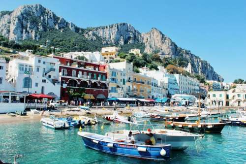 Buildings on a beach with boats. Mountains in the background.