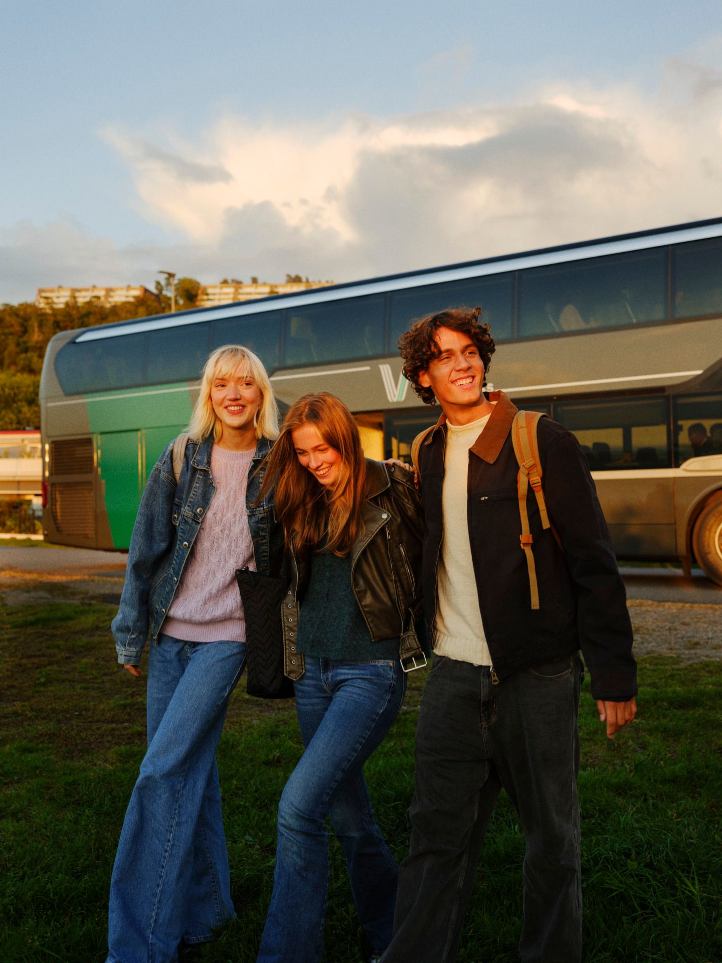 Tre unge mennesker går sammen vekk fra bussen.