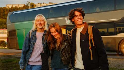 Three young people walking together away from the bus.