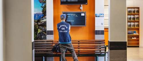 Resenärer står i avgångshallen och läser meddelanden på skärmen