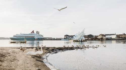 Strand og vann med båt i bakgrunnen.