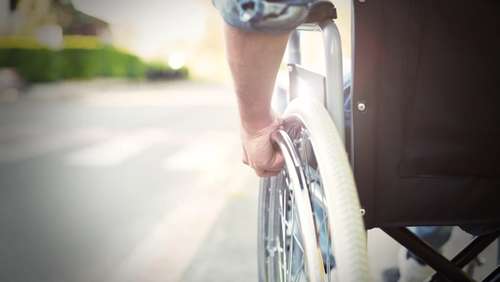 Close-up of wheelchair wheel with the user's hand on the wheel