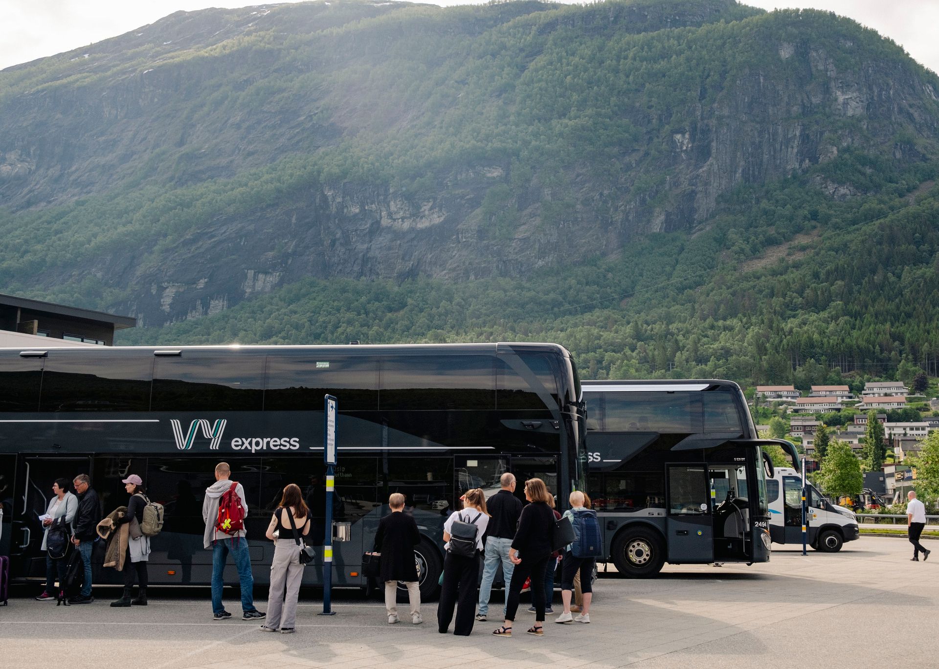 En turistbuss från Vy som står parkerad med människor på väg att stiga ombord på bussen.