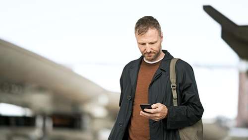 Man på plattform med mobiltelefon i handen