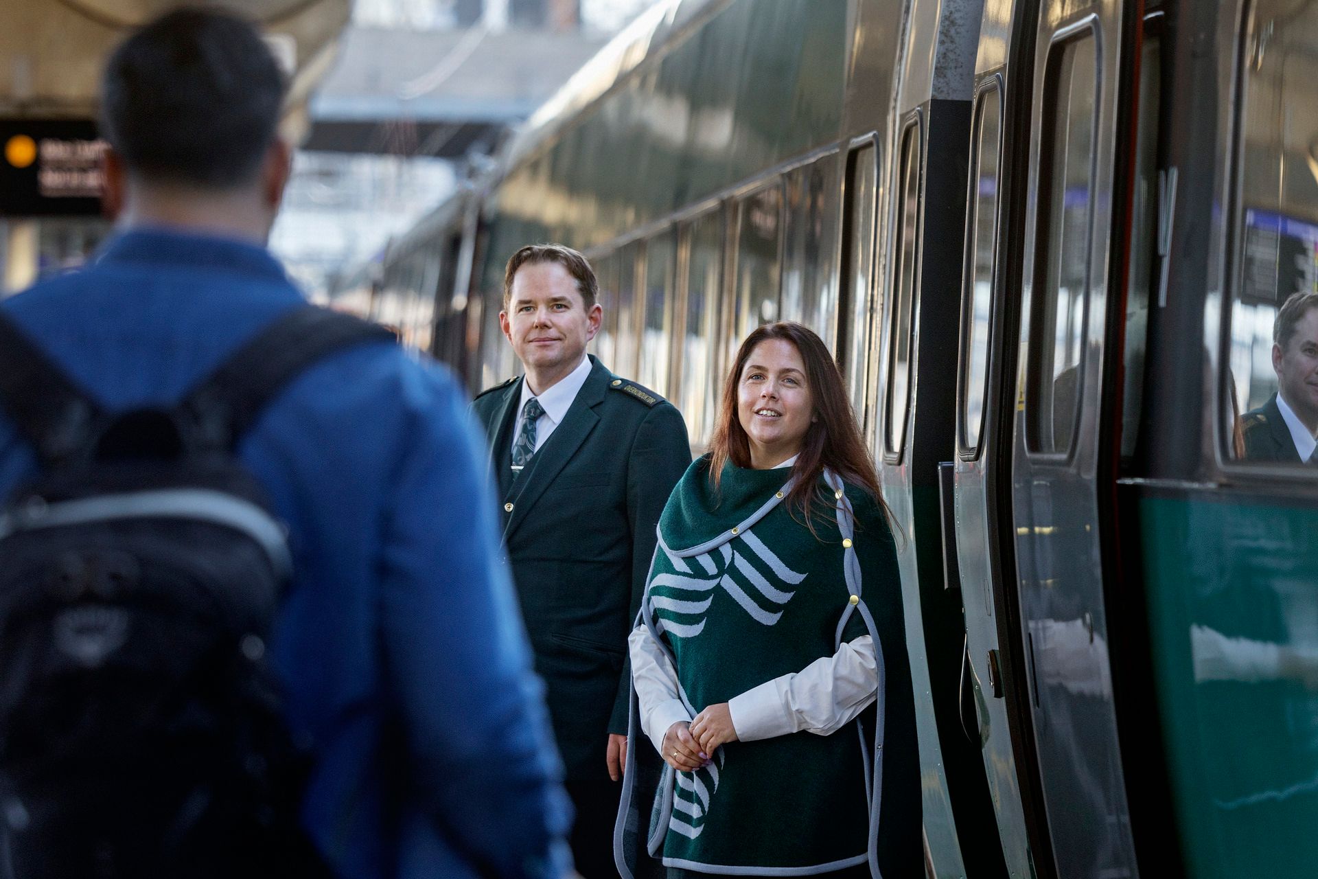 Konduktörer ler mot kunder på perrongen.