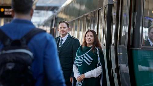 Conductor smiling with a passanger on the platform