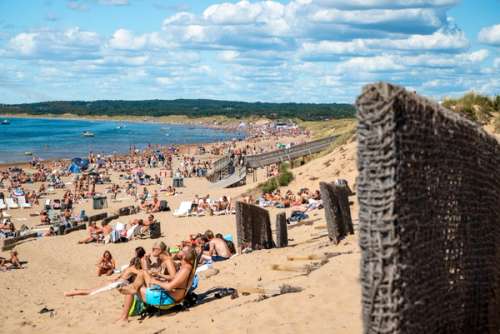 Tylösand i Halmstad med människor som solar och badar på en sandstrand en varm sommardag