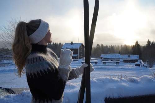 Flicka i vinterlandskap med skidor i handen